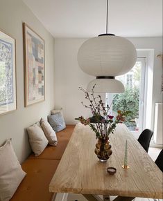 a wooden table topped with vases filled with flowers sitting next to a wall mounted art piece