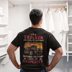 a man wearing a trucker t - shirt standing in front of a closet with his back to the camera