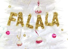 a white christmas tree with gold letters and ornaments on the top that says fala