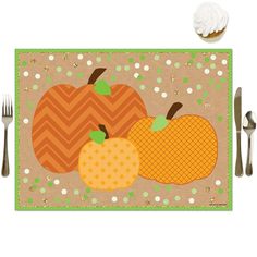 a placemat with two pumpkins on it next to silverware and a cupcake