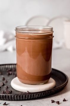 a glass jar filled with chocolate pudding on top of a black plate next to a cup