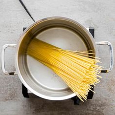 spaghetti being cooked in a saucepan with a spatula on the side and an open lid