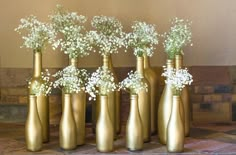 six gold vases with baby's breath flowers in them