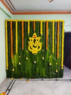 a wall decorated with yellow flowers and bells in front of a green backdrop that says ganeshi