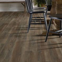 a dining room table and chairs with wood flooring in the background, along with a kitchen island