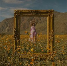 a woman standing in a field with a frame on it's face and her hands behind her head