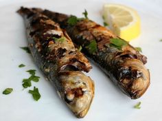 two cooked fish on a plate with lemon wedges