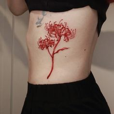 a woman's stomach with a red flower tattoo on her side and the bottom part of her body