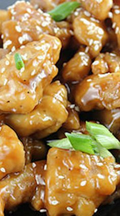 chicken with sesame seeds and sauce on a black plate