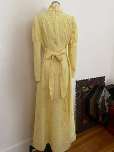 DESCRIPTION*60s Long Sleeve Maxi Dress in pale yellow *A mixture of Daisy foliage and polka dot flowers*Lightweight, slightly textured Polyester material *High Mandarin Collar with Puffy Sleeves and an empire Waistline*Belt that frames the empire waistline and ties in the back*Fitted silhouette with slight flair in the skirt*Pleating on the Bust*Zipper Closure from top to bottom*Perfect for a wedding or a 60s costume!DETAILS*Label: Handmade*Size: Small to Medium, see measurements below*Color: Pa Yellow Retro Vintage Dress For Garden Party, Yellow Vintage Dress For Garden Party, Spring Yellow A-line Vintage Dress, 1970s Style Yellow Spring Dress, Cream Vintage Dress For Spring, Yellow Vintage A-line Dress For Spring, Yellow A-line Vintage Dress For Spring, Vintage Maxi Dress For Spring, Spring Vintage Maxi Dress