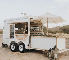 a food truck parked on the side of the road with an open umbrella over it