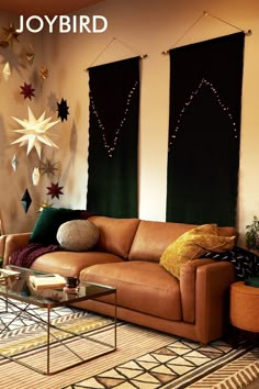 a living room filled with furniture next to two large window covered in hanging stars on the wall