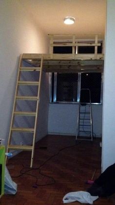 a ladder is in the middle of a room with a window and light on it