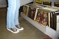 there is a person standing next to a rack full of cd's and cds