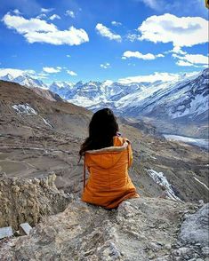 a woman sitting on top of a mountain looking at the mountains