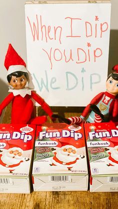 two elfs are sitting next to boxes of fun dip snacks and a sign that says, when i dip you dip we dip