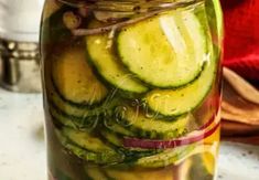 a jar filled with sliced cucumbers sitting on top of a counter