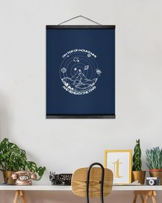 a framed poster hanging on the wall above a table with chairs and potted plants