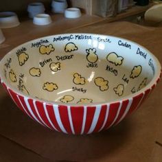 a red and white striped bowl with popcorn written on it