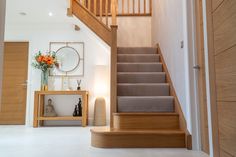 a staircase leading up to a living room with flowers in vases on the table