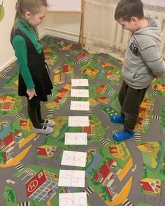 two young children standing in front of a play area with lots of paper on the floor