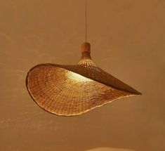 a woven lamp hanging from a ceiling in a room with beige walls and flooring