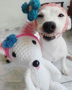 a white dog is next to a crocheted stuffed animal