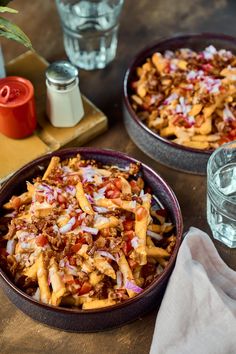 two bowls filled with food sitting on top of a wooden table next to water glasses