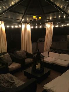 a living room filled with lots of furniture under a roof covered in lights and curtains