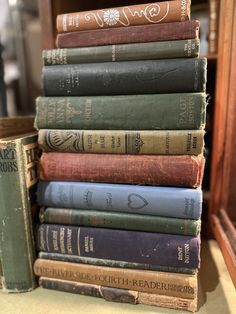 a stack of old books sitting on top of a wooden book shelf next to a mirror