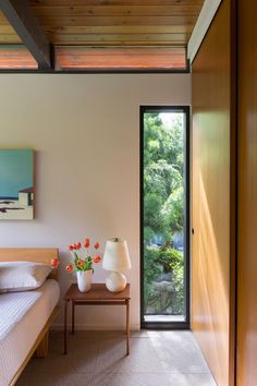 a bed room with a neatly made bed and two vases on the side table