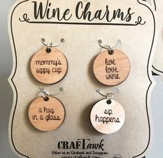 three wine charms with words on them hanging from a card board that says, wine charms