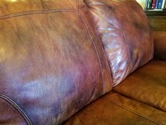 a brown leather couch sitting in front of a book shelf