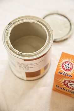 a can of paint sitting on top of a bed next to a box of glue