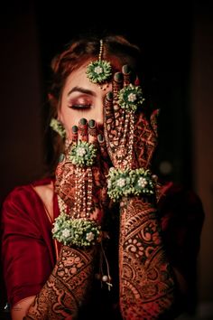 a woman holding her hands up to her face with henna and jewels on it