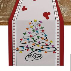 a cross stitch christmas tree with mickey mouses on it and red ribbon hanging from the back