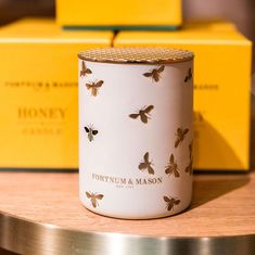 a white and gold candle sitting on top of a wooden table next to yellow boxes