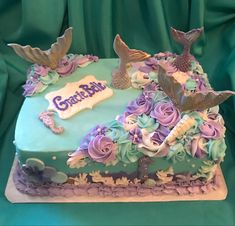 a birthday cake decorated with purple and blue flowers on a green tableclothed background