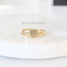 This ring features a heart shaped, brushed gold center signet (perfect for engraving) with ridged outlines on the shoulders. Perfect for everyday wear, this ring would make a great customizable gift for any occasion! Metals: solid 10k yellow gold heart center signet (approx. 7 mm)  solid 10k yellow gold band Please allow up to 5 business days for processing.  | c u r a t e d | Visit our website for curated and modern pieces  https://www.menkduke.com | f a c e b o o k | Follow us on Facebook for Heart Signet Ring, Heart Center, Signet Rings, Customizable Gifts, Bridal Gift, Bridal Gifts, Heart Of Gold, Signet Ring, Gold Bands