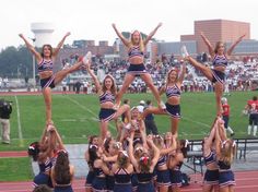 the cheerleaders are doing stunts on the track for their team to perform in