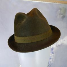 This classic 1960s German vintage olive brown smooth rabbit fur felt trilby hat has a 1.5-inch (3.81cm) brim and a 1-inch (2.54cm) band. The water-repellent fedora is lined in an black satin viscose fabric. Note that all hats I sell have been professionally cleaned and sanitized. Brand label: Ottmar Reich (Germany) Size: Small US = 6 7/8 UK = 6 3/4 EU = 55 Inches = 21 5/8 (54.93cm) Top front to inner brim = 3.5 inches (8.89cm) Condition: Excellent (clean, soft, and supple, with no stains, tears, Gold Bodysuit, Satin Noir, Long Overcoat, Trilby Hat, Vintage Rabbit, Felt Fedora, Vintage Clothing Men, Trench Coat Black, European Vintage