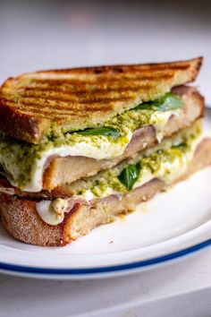 a grilled sandwich with pesto and cheese on toasted bread, sitting on a plate