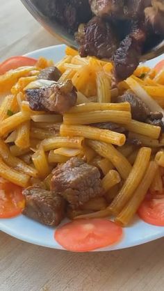 a plate full of pasta with meat and vegetables on it next to a bowl of sauce