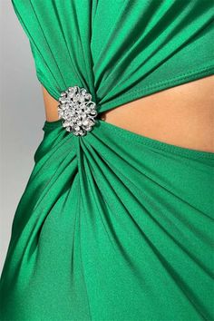 the back of a woman's green dress with a crystal brooch on it