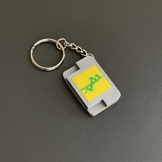 a gameboy keychain with the letter a on it's front and back side