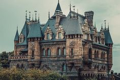 an old castle like building with towers and turrets on top is surrounded by greenery