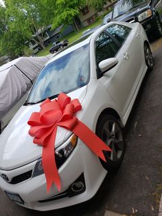 a white car with a red bow tied to it