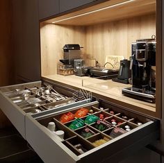 an open drawer in a kitchen filled with coffee and other items on top of a counter