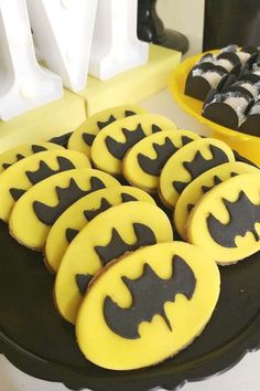 batman cookies are arranged on a plate with black and yellow icing for the top