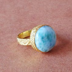 Add some color to your ring collection with this highly gold polished brass statement ring. Round-shaped larimar gemstone is bezel-set throughout for a stunning style. 18K Gold Plated Ring, Natural Larimar Ring, Round Gemstone Ring, Cabochon Ring, Larimar Jewellery, Perfect Birthday Gift Ring For Women Product Details Item Code: BJBR-1247 Stone Name: Larimar  Stone Shape: Round Stone Size : 18mm Metal: Yellow Gold Plated Over Brass  Ring Size: Please choose from drop down menu. If you do not see Gold Turquoise Ring Gift, Gold Turquoise Ring For Gift, Larimar Cabochon Jewelry Gift, Round Larimar Jewelry For Gifts, Round Larimar Jewelry Gift, Round Larimar Rings As A Gift, Birthday Gift Ring, Larimar Ring, Larimar Rings